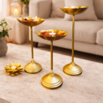 Set of three gold metal urli bowl tealight holders with stands, decorated with floating candles and flower petals for festive home decor.